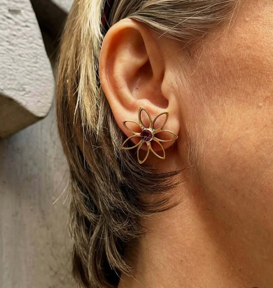 Orecchini in bronzo Margherita con granati rossi indossati da una donna, eleganza e natura in un unico accessorio.